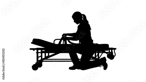 Silhouette of woman kneeling by gurney in black and white setting