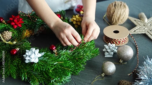 Close-up of small hands holding a decorated Christmas wreath during a holiday craft activity. A symbolic moment of festive creativity and childhood involvement in home traditions.