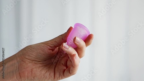 Close-up of a pink menstrual cup standing upright on a woman open palm over wooden table. Feminine hygiene product promoting zero waste, comfort, and sustainable period care.