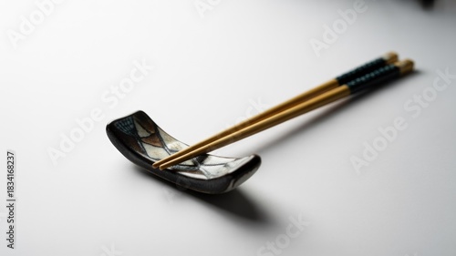 Wallpaper Mural Elegant wooden chopsticks with dark accents rest on a decorative patterned ceramic chopstick holder, presented against a clean white background. Torontodigital.ca