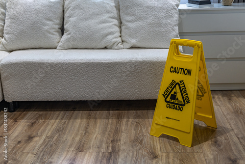 Photos A yellow wet floor warning sign placed on new vinyl flooring in an office, warning about the slippery surface