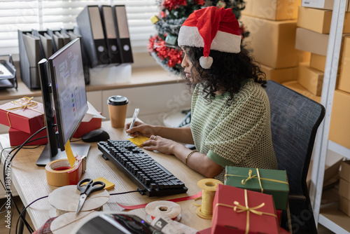 Small business holiday warehouse process showing a worker hold Christmas gifts, checking orders, arranging parcels, managing stock accuracy and coordinating ecommerce busy shipping for festive season