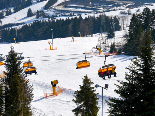 Empty Orange Ski Chairlift Ascending a Snowy Mountain Slope