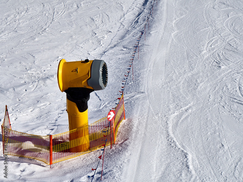 Yellow Snow Cannon on a Ski Slope with Safety Netting