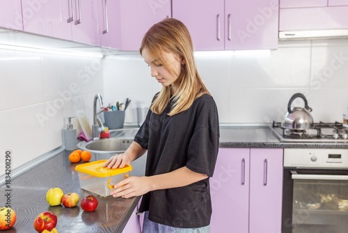 Girl storing fresh fruit in kitchen container