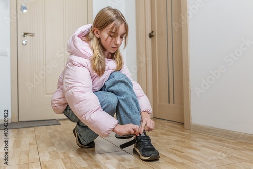 Girl tying shoelaces before going outside in winter