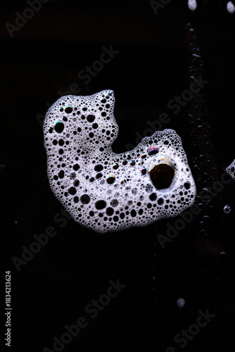 Curious bubbles form the outline of a face against a black background, creating a visually intriguing and abstract scene. The contrast highlights the bubbles' playful shapes.
