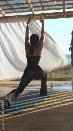 A woman in a twisted lunge yoga pose on a breezy patio