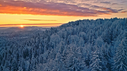 Fototapete Sonnenuntergang Breathtaking winter landscape at sunset, snow-covered evergreen trees under a vibrant, colorful sky. Serene beauty of nature in cold temperatures, contrasting icy forest with warm sunset hues.  © wkproduction