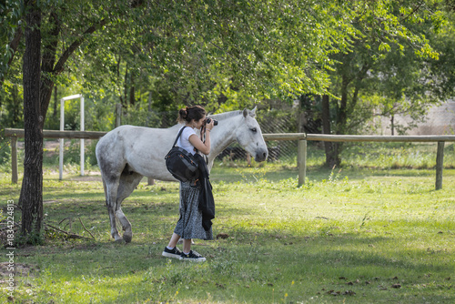 Girl taking a photograph next to a horse in Villa Giardino, Cordoba, Argentina.