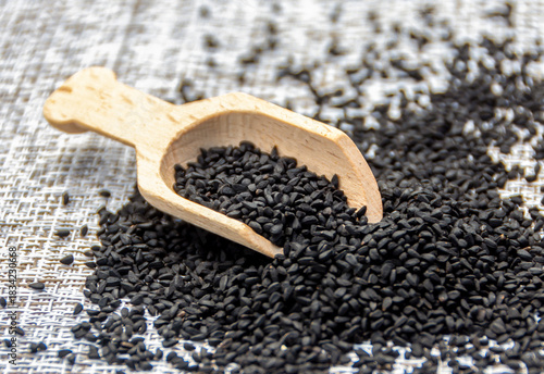 Bio natural black sesame seeds in a wooden spoon on a wooden bowl. Healthy eating, Ayurveda, spices, healthy food, alternative medicine