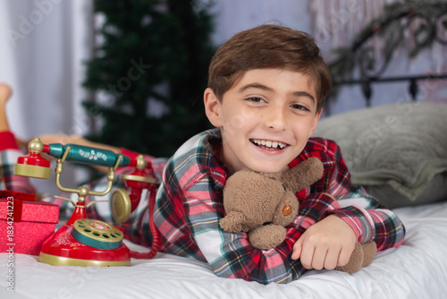 cute little boy on a bed in holiday pjs 8 years old 7 years old with teddy bear 