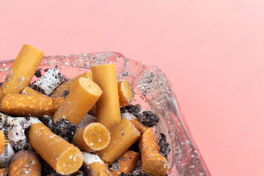 Fototapeta premium cigarette butts torn on pink background ashtray