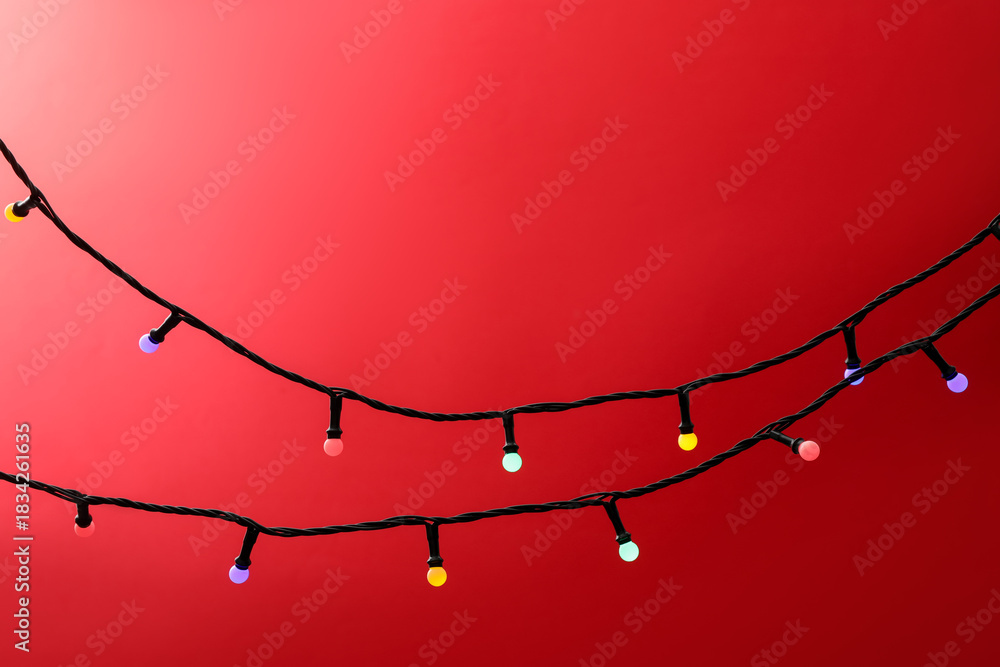 Naklejka premium Bright Christmas lights on red background, closeup. Space for text