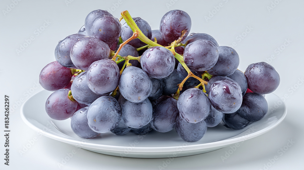 Fototapeta premium Close up shot of a bunch of dark purple grapes with water droplets on a white plate surface
