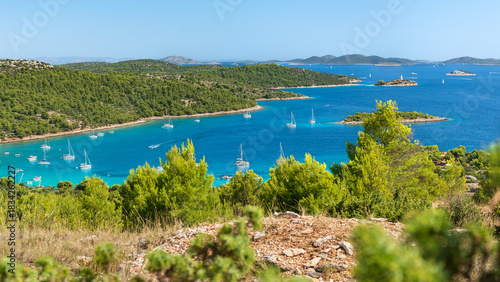 Croatian coastal landscape with small islands in the sea, green forest and blue water, view from a hill on a natural landscape on a sunny day.