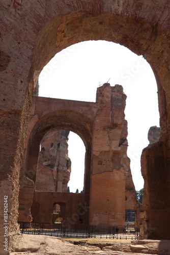 Impressive brick arches and towering ruins of ancient Roman public baths in Rome under a bright sky