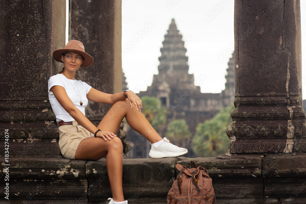 Naklejka premium Angkor Wat Columns With Female Traveler Sitting, Cambodia Tourism Concept