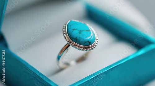 Silver ring with turquoise stone placed in a soft blue box indoors