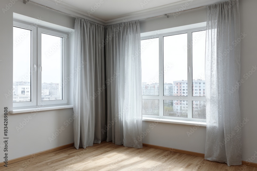 Fototapeta premium Empty room corner features two large windows with flowing light gray drapery covering parts of the exterior view