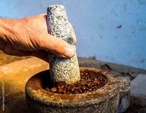 A person manually grinding aromatic coffee beans in a rustic stone mortar with a pestle for fresh