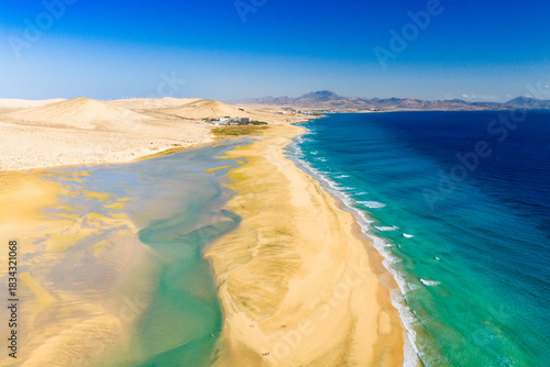 Playa de Sotavento is a famous beach on the southeastern coast of Fuerteventura, known for its long stretches of golden sand, turquoise water, and consistent winds