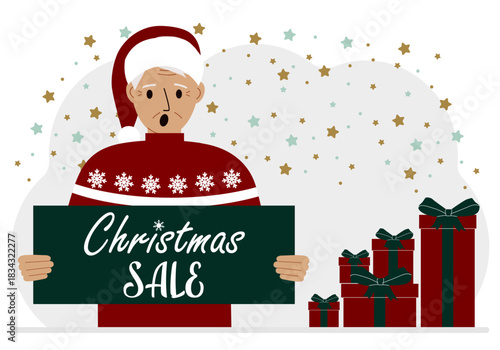 A man in a sweater and a red Santa hat holds a poster with the text about Christmas sale in his hand.