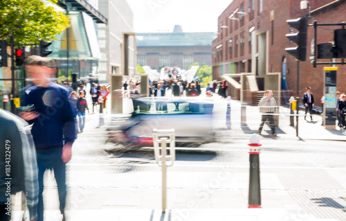 Crowd of people crossing road in the City of London at sunny day. Motion blur postmodernism style photo  