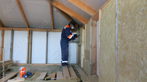 Insulation of a frame house with mineral wool. Cutting, fitting, laying insulation. Construction works.