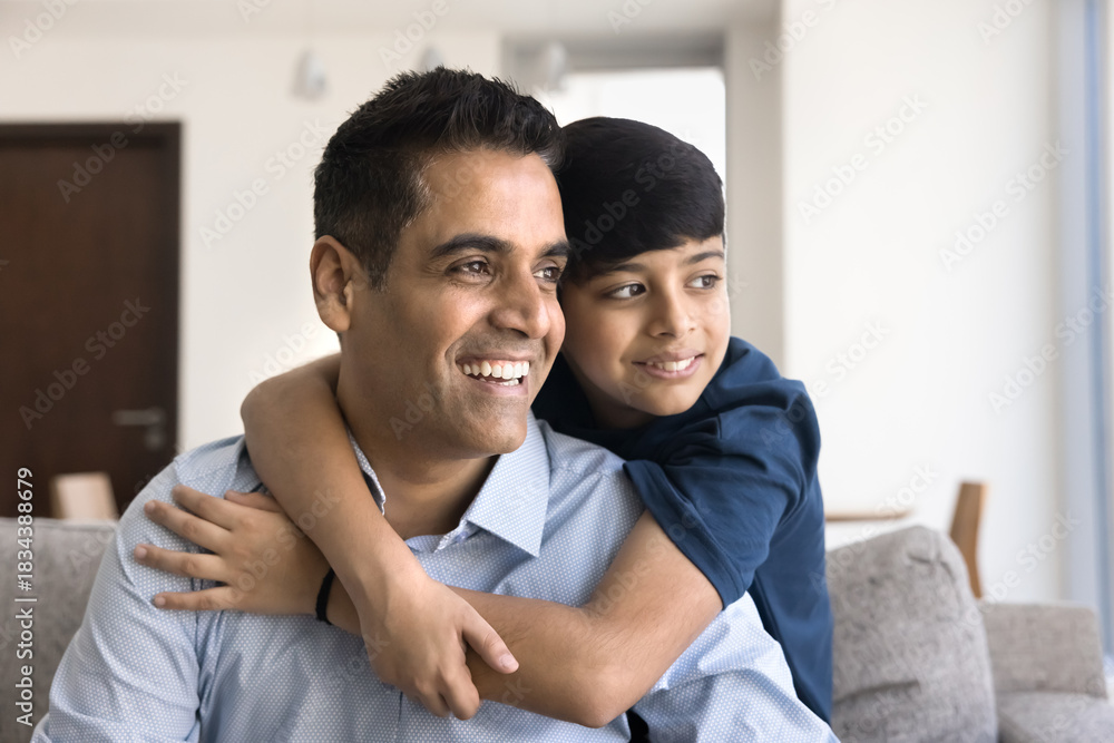 Fototapeta premium Loving Indian son cuddling from behind his handsome smiling father
