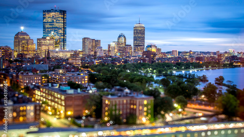 Conceptual image of Boston in Massachusetts, USA at night with blurred buildings and focus on background buildings.