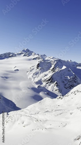 Ski resort view with cable cars moving over a snowy slope. A skier descends in the foreground. Foggy mountain backdrop adds a calm, wintry mood.
