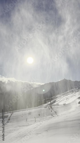 Panoramic view of snow-covered alpine peaks at sunrise or sunset. Soft sunlight creates a warm glow over the rugged, silent mountain landscape.