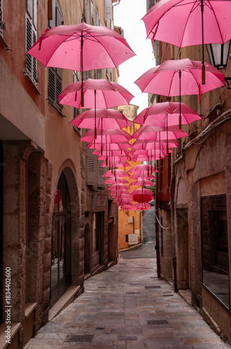 Fototapeta Naklejka Na Ścianę i Meble -   Streets of Grasse, a city known for its perfumery, decorated with pink umbrellas on the occasion of the annual international exhibition of roses - Expo Rose.