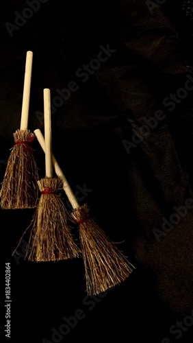 Mini witch brooms on black background, occult props, mystical composition, esoteric tools for magic and rituals
