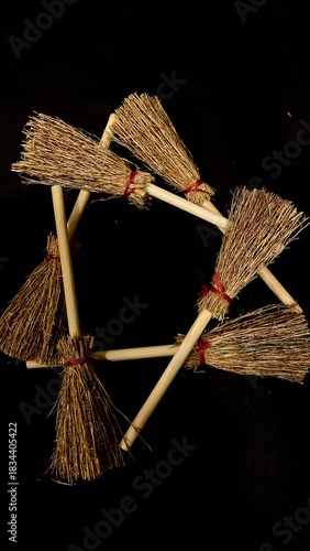 Mini witch brooms on black background, occult props, mystical composition, esoteric tools for magic and rituals