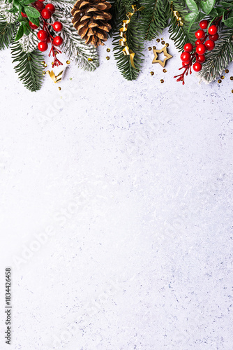 Festive Christmas border with fir tree branches and bright decorations on light blue marble background with copy space for your design top view. Vertical image.