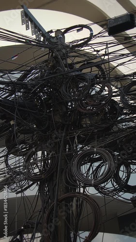 dense electrical cord bundles under cover form decorative knots with striking urban light and shadow interplay