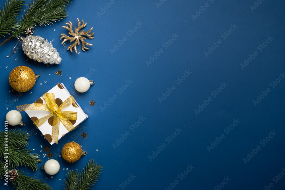 Naklejka premium White and golden Christmas decorations and gift box on navy background.