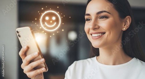 Woman Smiling While Holding Smartphone with Happy Face Icon.