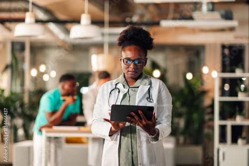 Black doctor using digital tablet in clinic