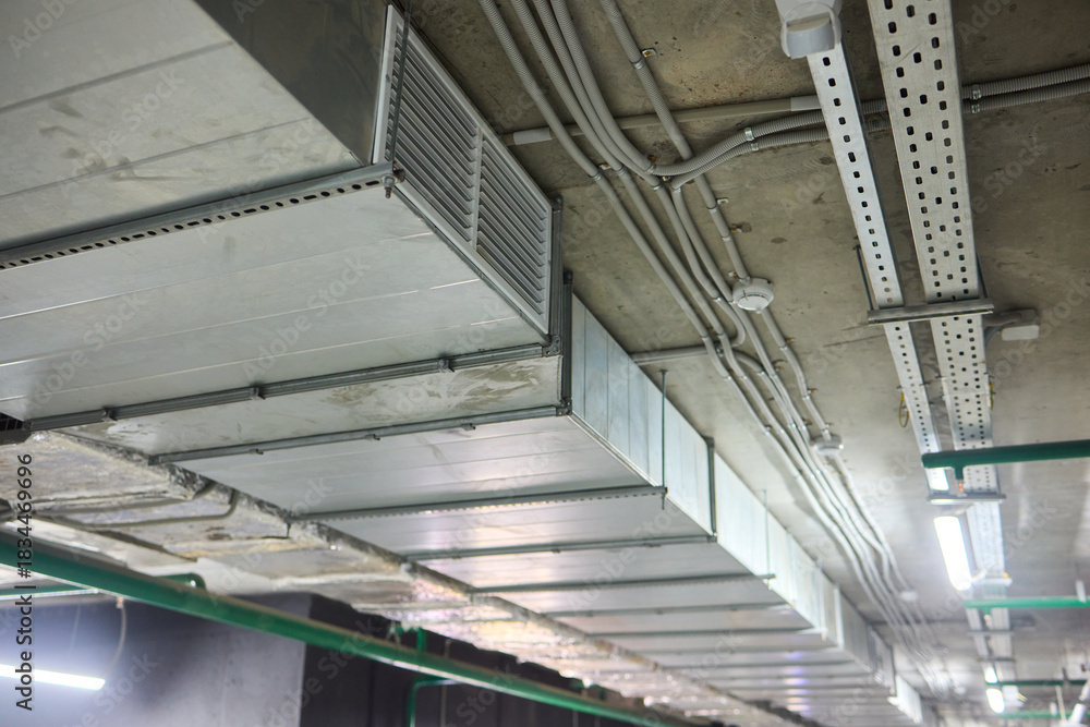 Obraz premium Subterranean parking details, Basement parking area equipped with lighting and plumbing, Underground vehicle shelter featuring electrical wiring and ventilation systems