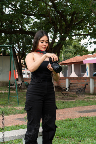 Beautiful girl taking a photo with a camera at the park.