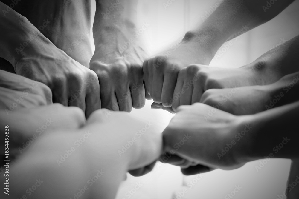 Naklejka premium Group of people holding their fists together, closeup. Black-and-white toning