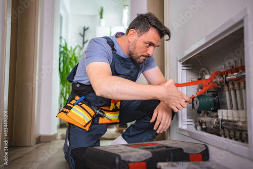 Photos Plumber fixing central heating pipes with red pipe wrench