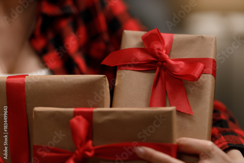A person holds several wrapped gifts with red ribbons, perfect for a special occasion