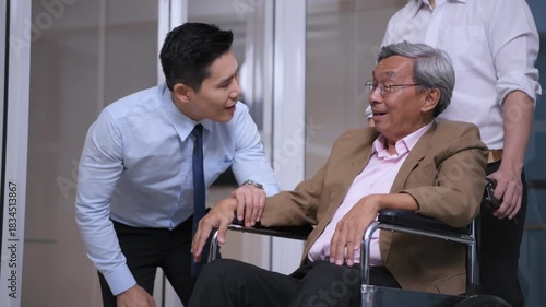 Business concept of 4k Resolution. Asian man talking and giving encouragement to an elderly person in a wheelchair in the office.