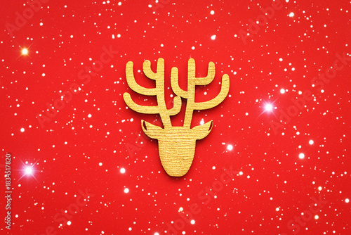 A deer head on a red background with bright lights. A decorative wooden figurine. A symbol of Christmas. Concept: Christmas, New Year, gifts, holidays. Minimalism. Flat lay.