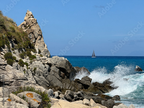 Mediterranean Sea in Calabria, Italy, sailing yacht and sea surf among rocks