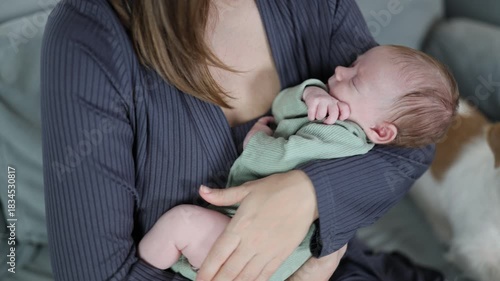 A woman is caring for her baby. The mother is rocking the baby in her arms. The newborn is sleeping. A close-up of the baby in the woman's arms.